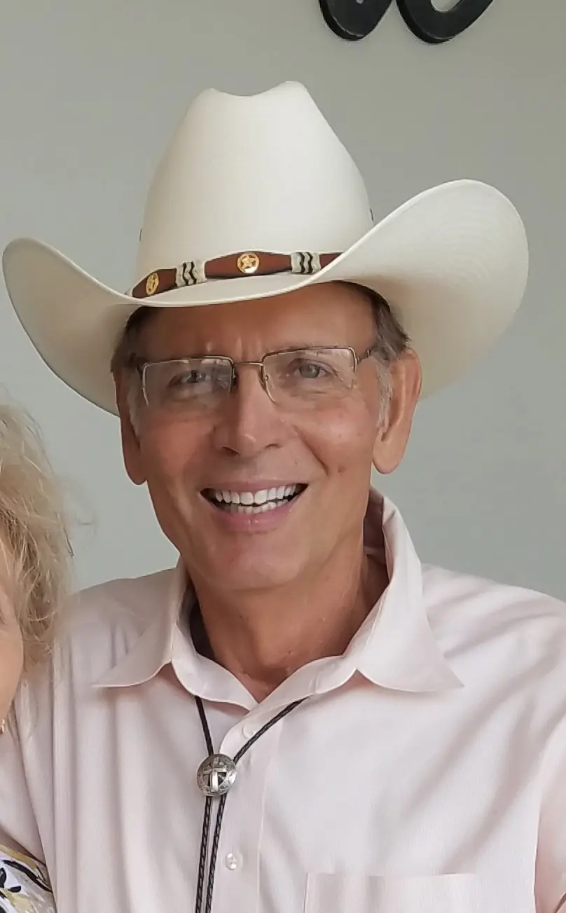 Smiling man wearing glasses and a white cowboy hat.