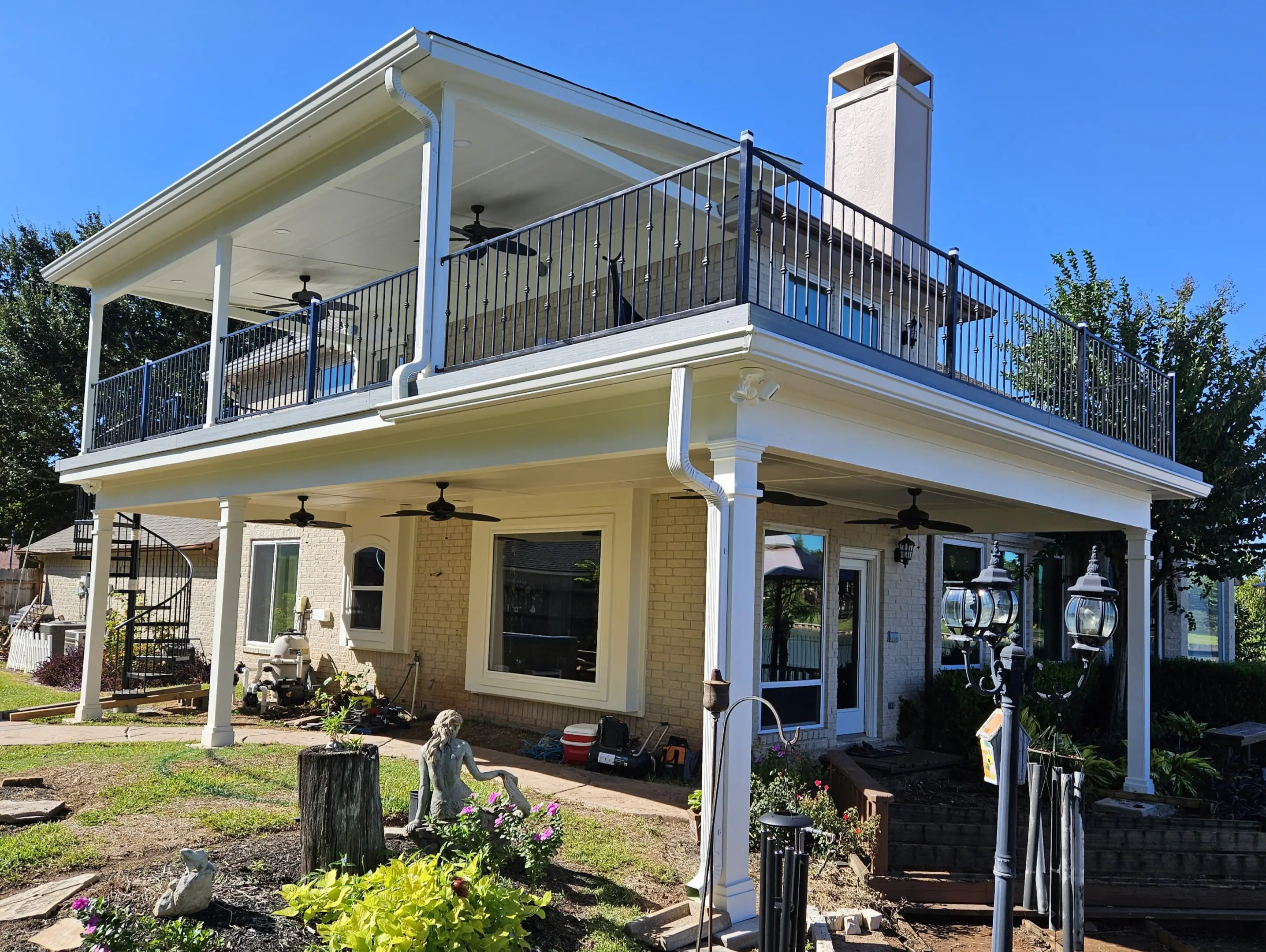 A two-story yellow house with a balcony and outdoor seating area.