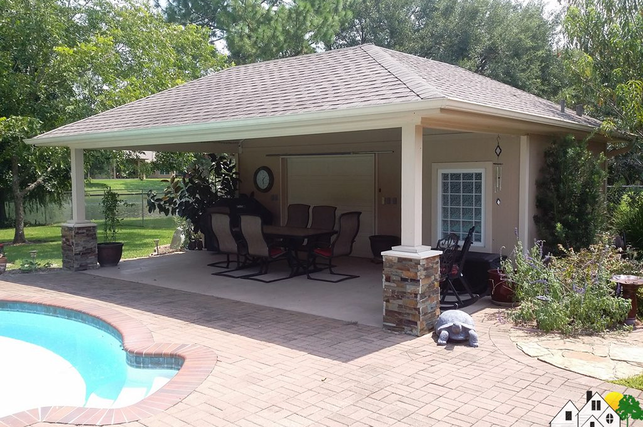 Covered patio with outdoor furniture near a pool in a backyard.
