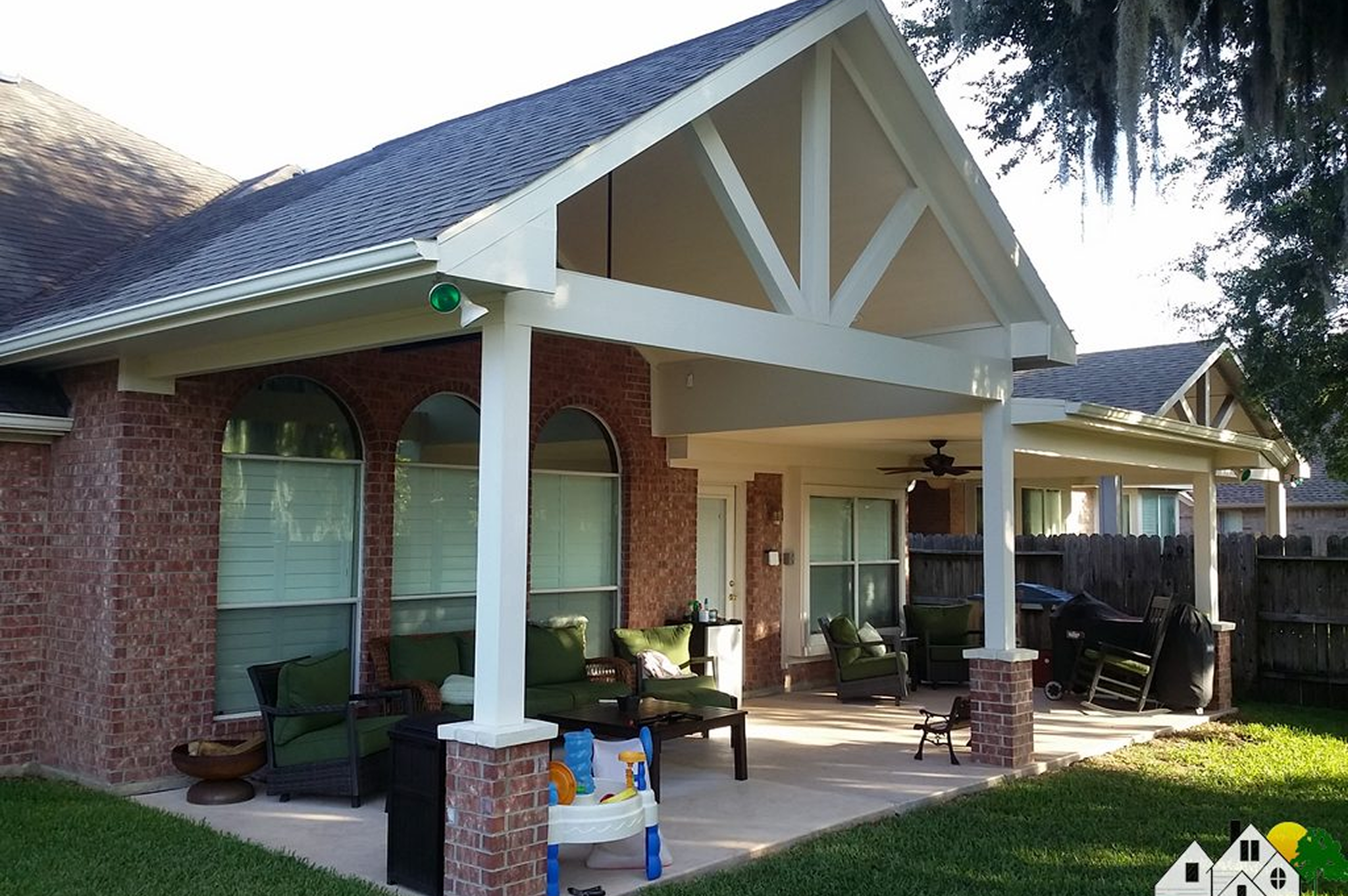 A cozy porch with white columns and outdoor seating under a gabled roof.