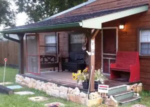 Cozy porch with wooden benches and potted flowers outside a rustic cabin.
