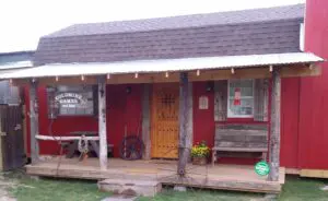Rustic wooden cabin entrance with a yellow door and porch bench.