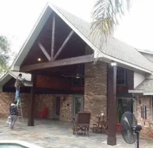 A rustic outdoor patio with a wooden roof and stone pillars.