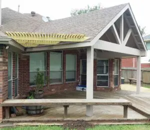 A house patio with a wooden pergola and a concrete bench.