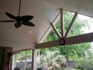 Ceiling fan and clock on a cozy porch with a view of greenery.