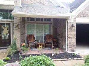 Cozy porch with two wooden chairs and a small table between them.