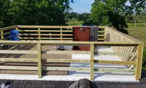 A wooden deck with a hot tub and a scenic view of trees and fields.