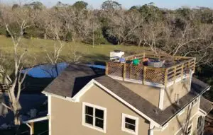 A rooftop deck with furniture and a view of trees and water.