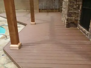 Newly installed brown wooden deck with sturdy posts and brick pillars.