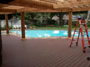 Covered patio overlooking a clear swimming pool in a backyard.