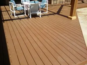 A wooden deck floor with outdoor furniture in sunlight.