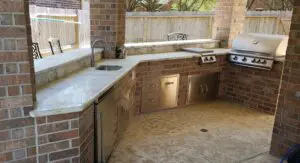 Outdoor kitchen with marble countertops and built-in cabinets.