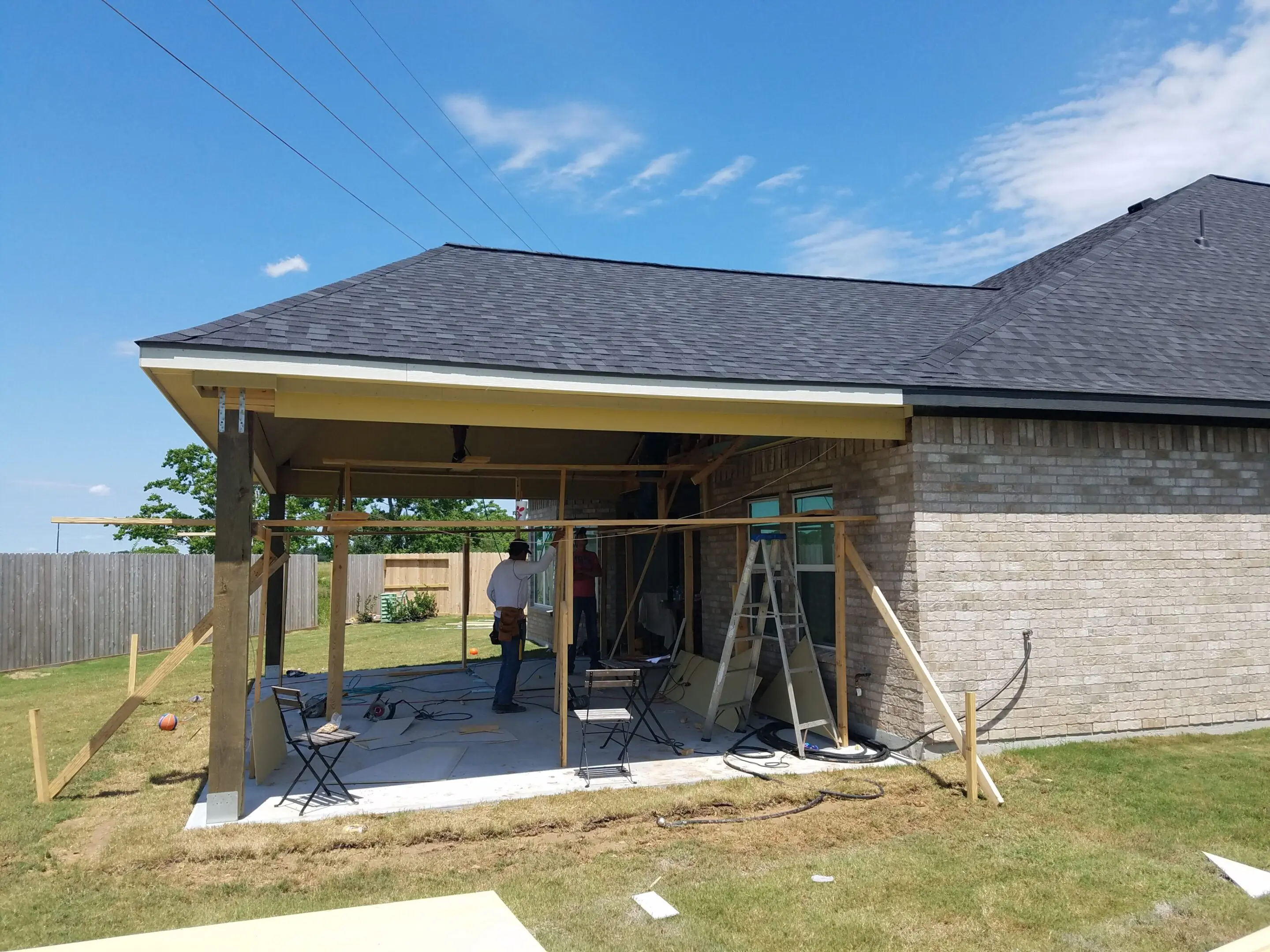 Construction workers building a covered patio on a sunny day.