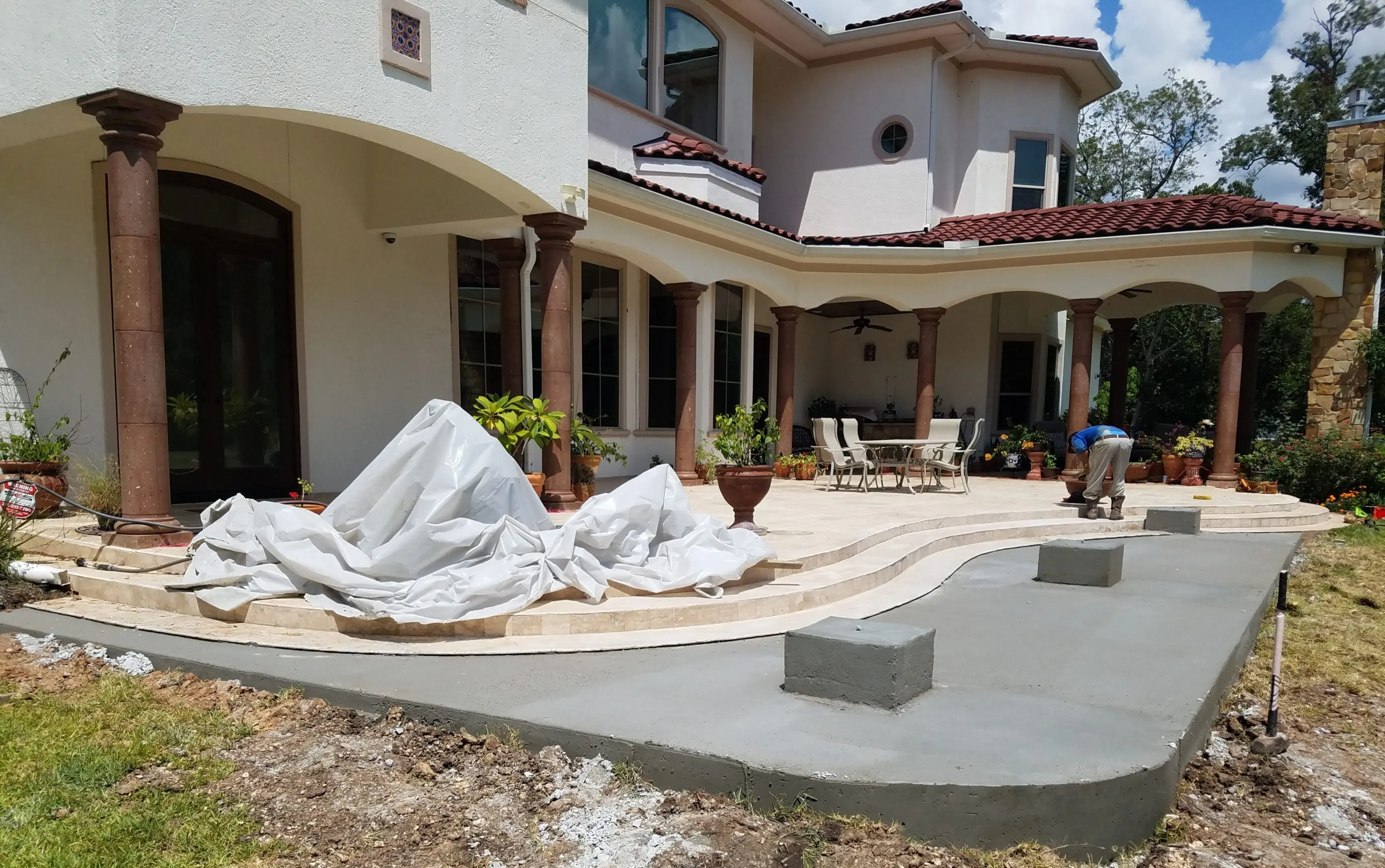 Two people relaxing on white lounge chairs by a house patio.