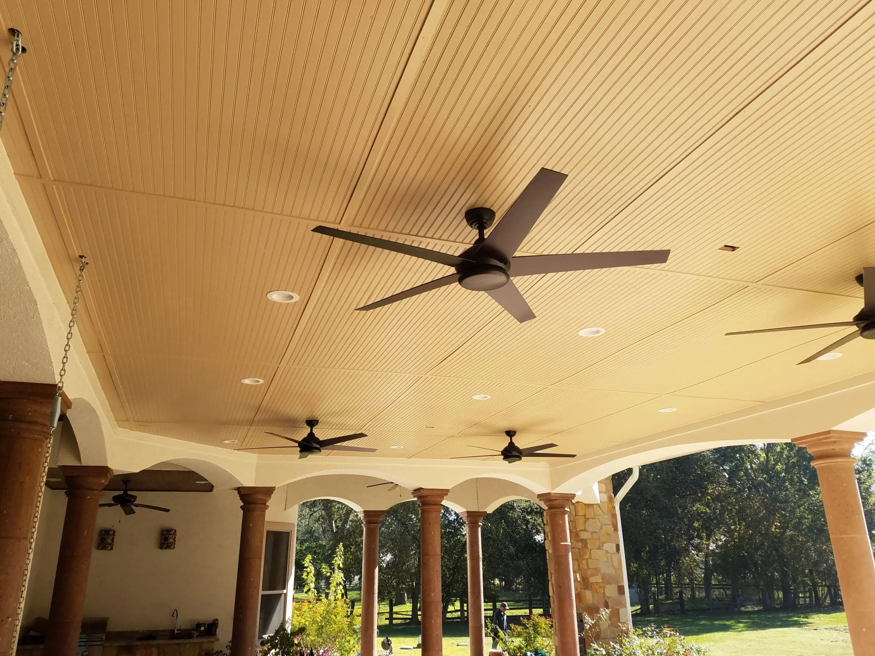Ceiling fans installed on a beige outdoor patio roof.