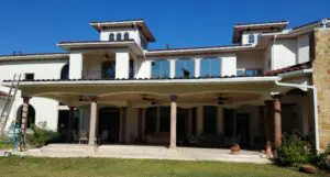 A modern two-story house with white walls and a balcony under a clear blue sky.