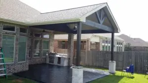 Covered outdoor patio with brick columns and grill area.