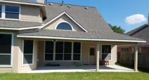 A beige house with a large window and a sloped roof under clear blue sky.
