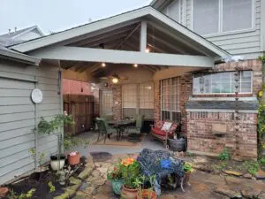 Cozy covered patio with string lights and potted plants.