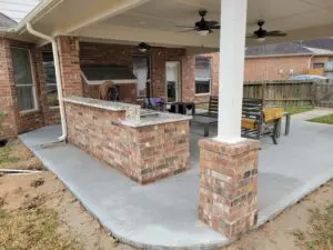 Outdoor brick bar with ceiling fans and concrete floor.