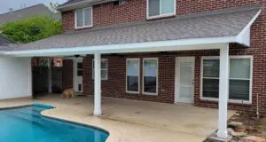Covered patio beside a swimming pool with a dog nearby.