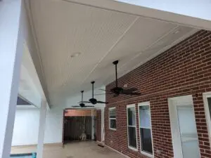 Covered patio with ceiling fans and brick wall.