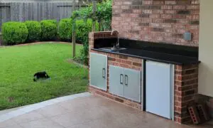 Outdoor kitchen setup with a grill, sink, and refrigerator.