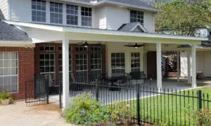 Cozy backyard patio with furniture and a pergola attached to a two-story house.