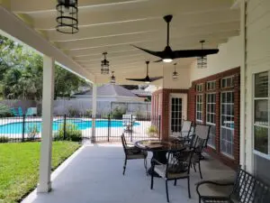 Spacious covered patio with seating overlooking a backyard pool.