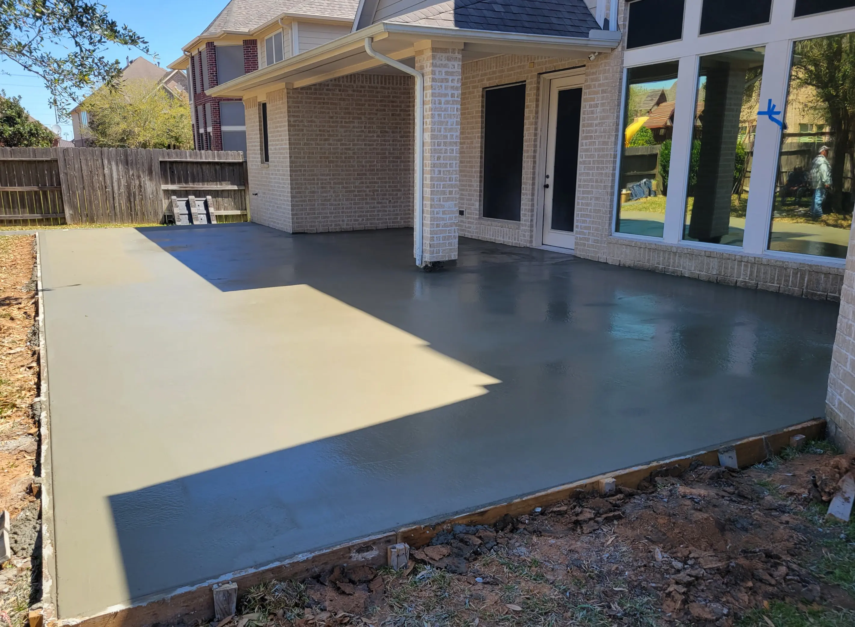 Newly poured concrete patio drying beside a house.