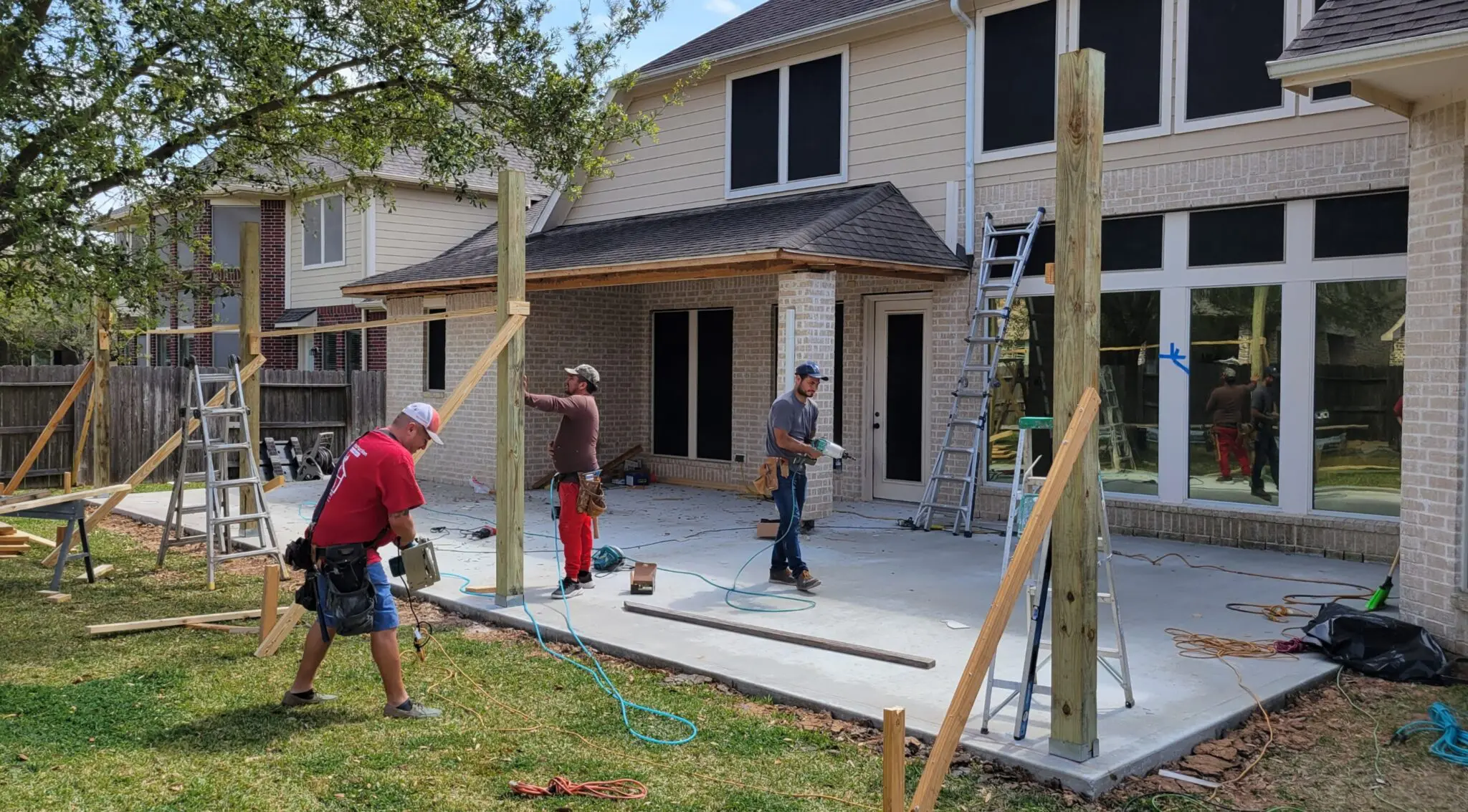 Workers preparing a residential concrete patio on a sunny day.
