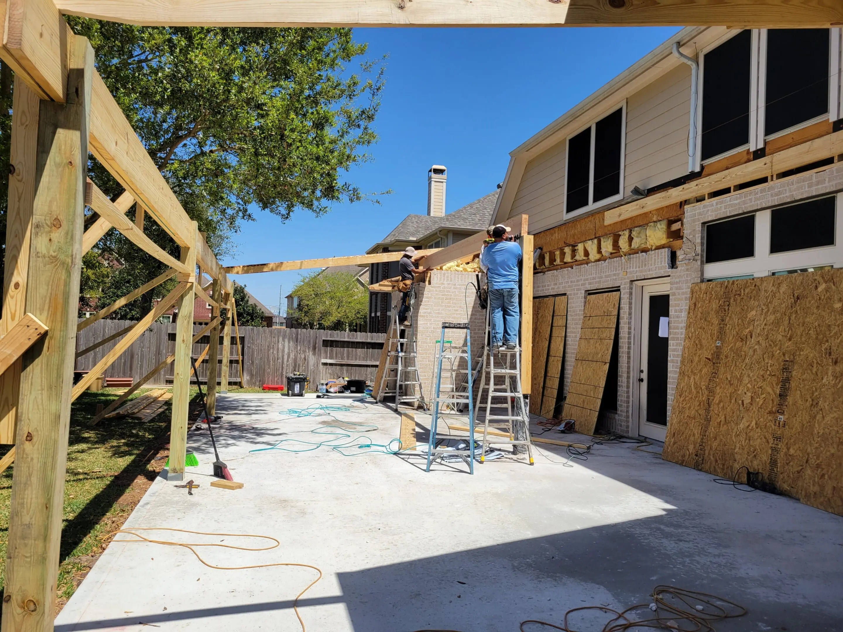 Construction workers renovating a building exterior under clear blue sky.