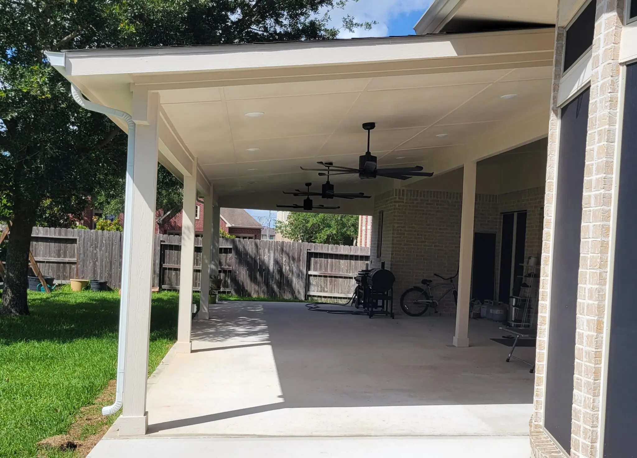 Empty covered patio area with ceiling fan and concrete floor.
