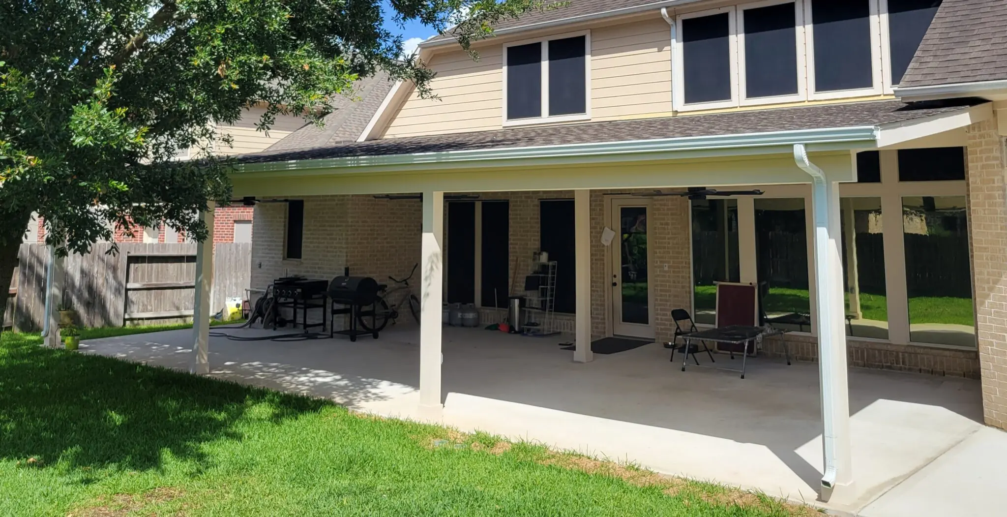 Backyard patio with covered seating area and lawn.