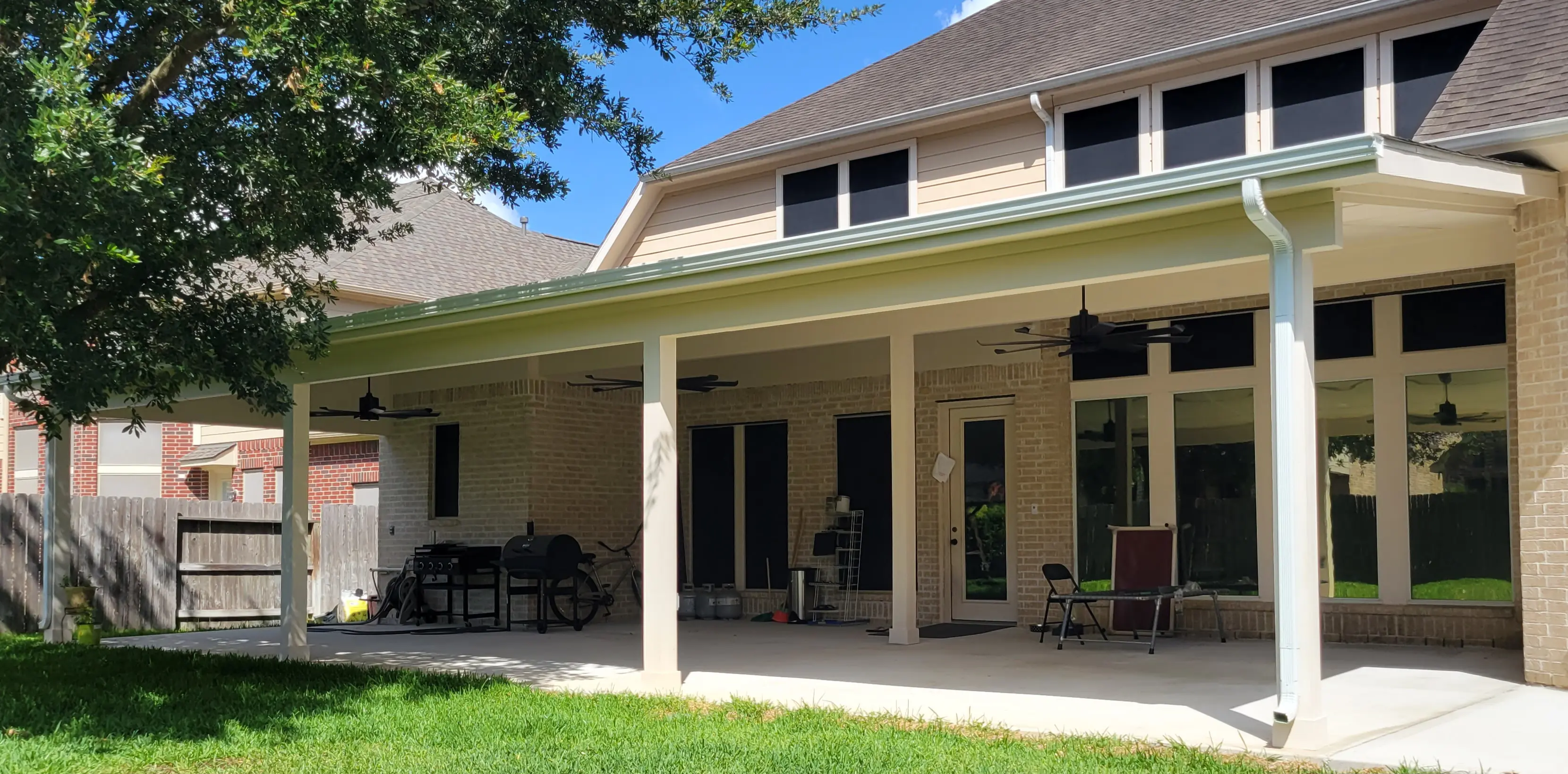 Spacious backyard patio with outdoor seating and ceiling fans under a covered porch.