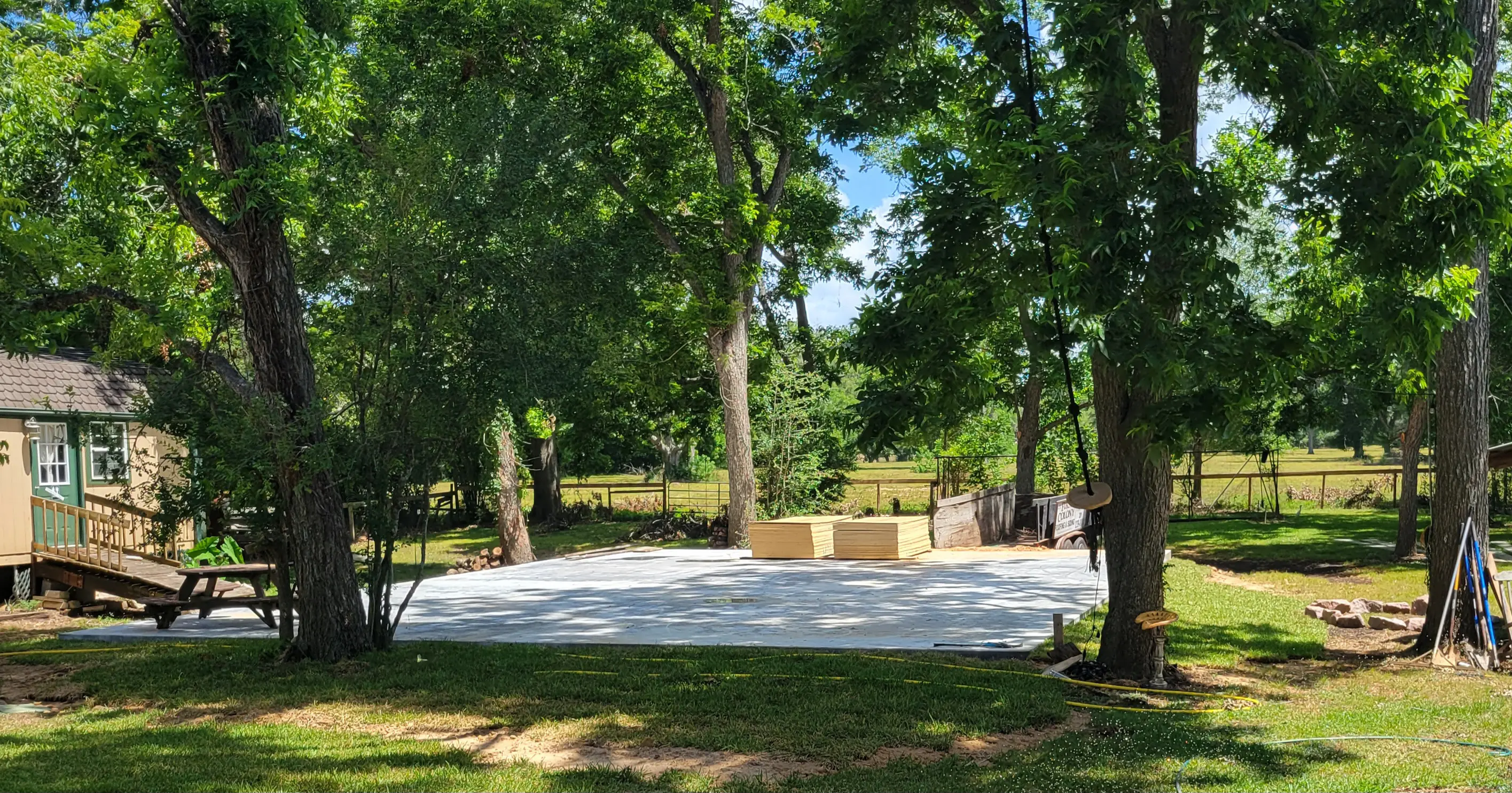 A backyard with a large patio surrounded by trees and greenery.