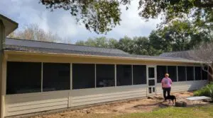 A man standing near a newly built screened-in porch on a house.