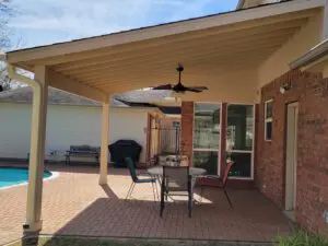 Cozy backyard patio with a table, chairs, and a ceiling fan under a covered roof.
