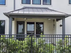 Modern house entrance with glass doors and a metal fence.