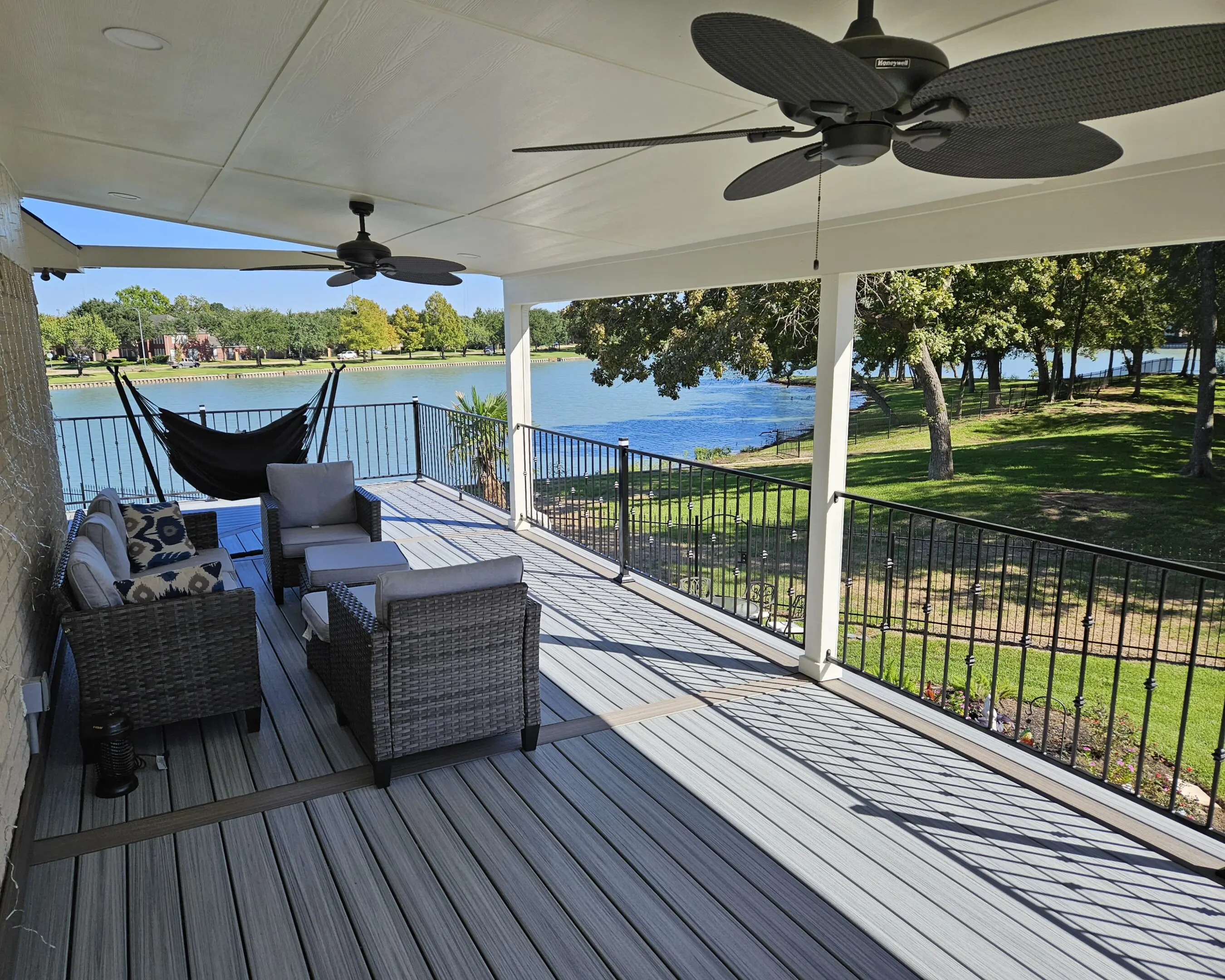 Spacious porch with ceiling fans overlooking a serene waterfront.