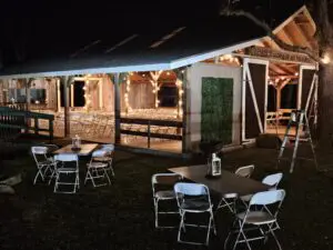 Cozy outdoor gathering area with string lights and folding chairs at night.