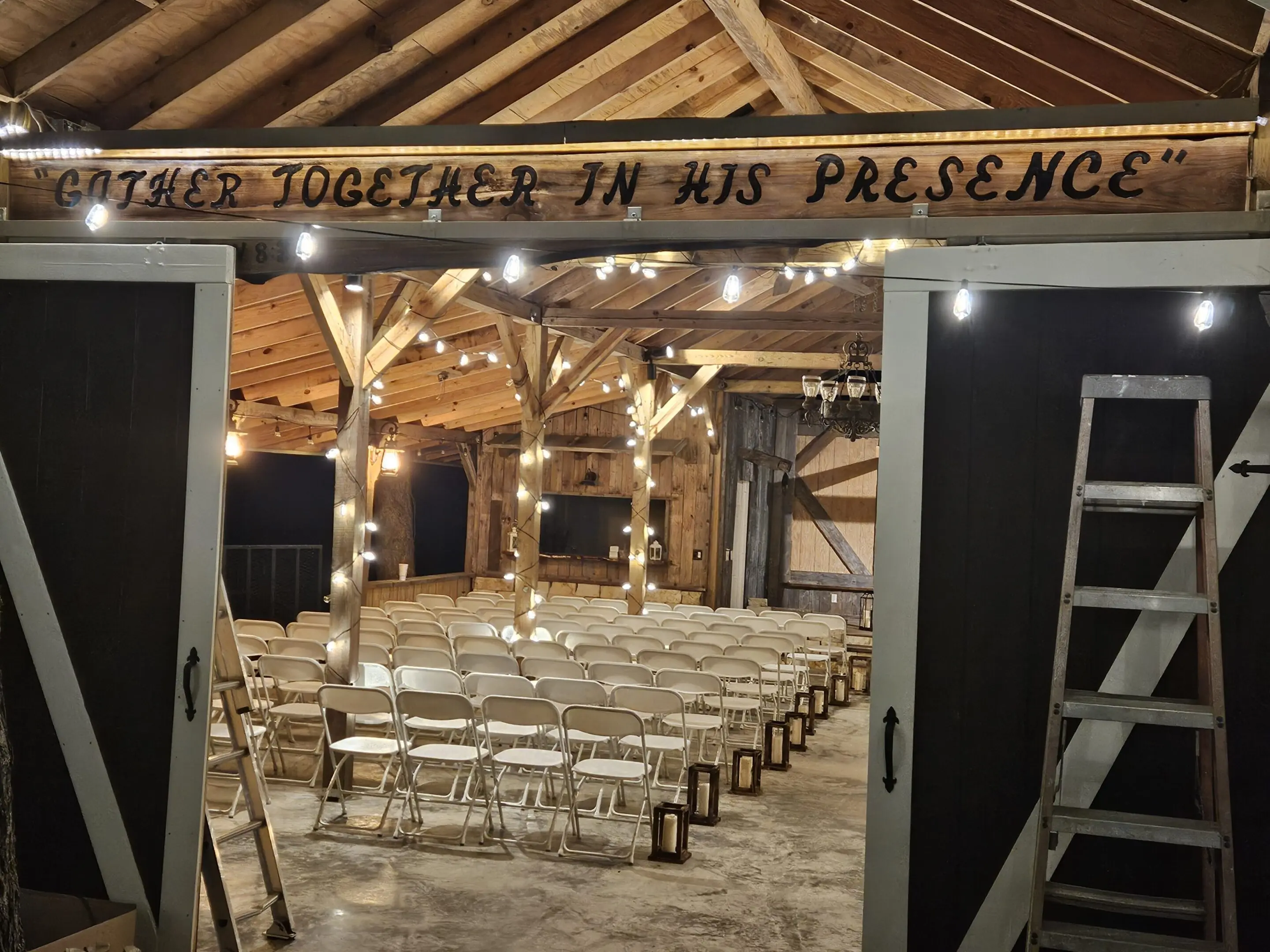 Rustic indoor wedding venue with wooden beams and string lights.