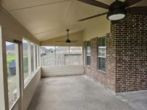 Spacious covered patio with ceiling fans and large windows.