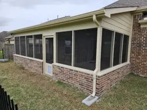 Screened-in porch attached to a brick house with a sloped roof.