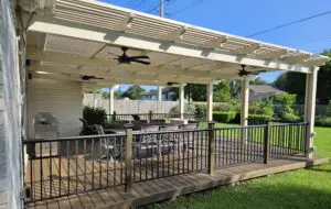 Outdoor patio with pergola, seating area, and ceiling fans on a sunny day.