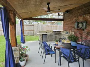Cozy backyard patio with dining table and ceiling fan under a wooden pergola.