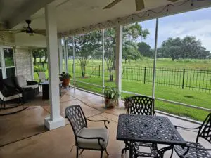 Cozy patio with wrought iron furniture overlooking a lush green field.