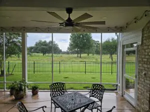 Cozy patio with ceiling fan overlooking a green fenced yard.