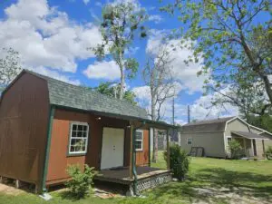 Small wooden house with a porch under a blue sky with clouds.