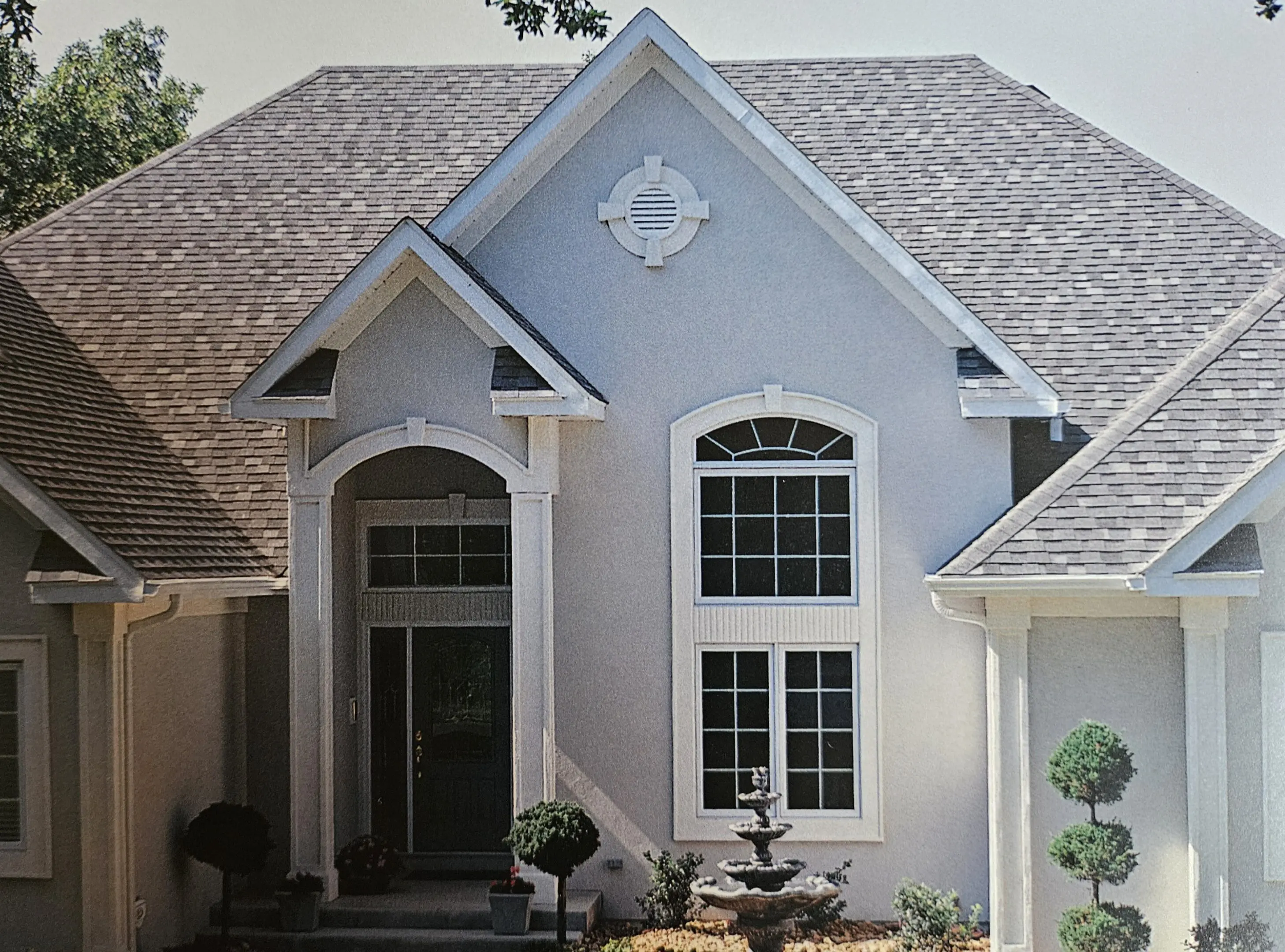 Elegant light gray house with large windows and a tiled roof.
